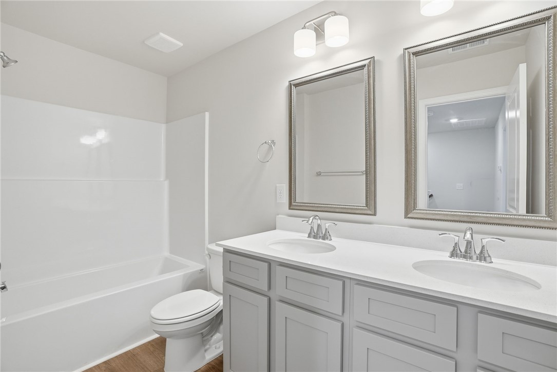 305 Lilac Loop Greenwood, SC 29646 - Photo 17 of 25 A well-lit bathroom featuring a clean double vanity and a shower-tub combination.