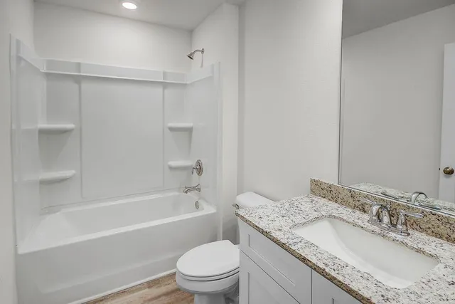 a bathroom with a granite countertop sink a toilet and bathtub