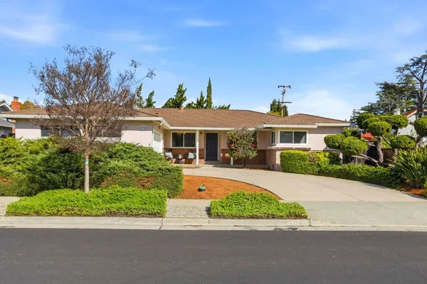a front view of a house with a yard and potted plants