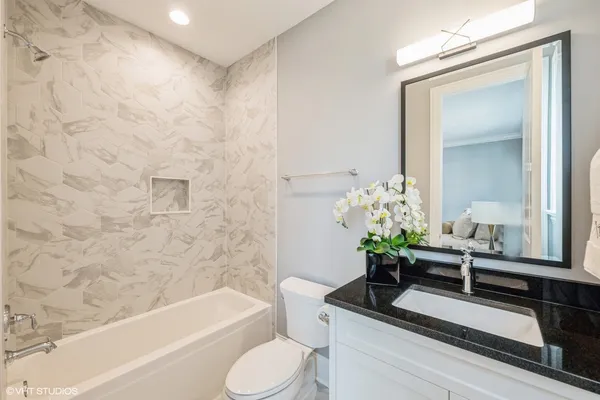 a bathroom with a granite countertop sink a toilet and bathtub