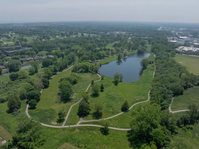 an aerial view of residential house with outdoor space and trees all around