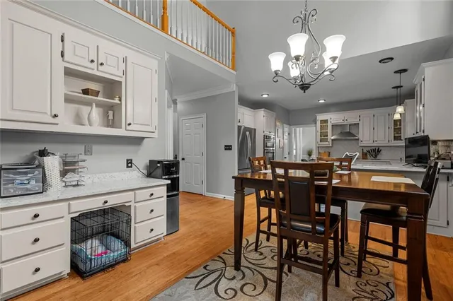 a kitchen with stainless steel appliances kitchen island granite countertop a dining table chairs and white cabinets