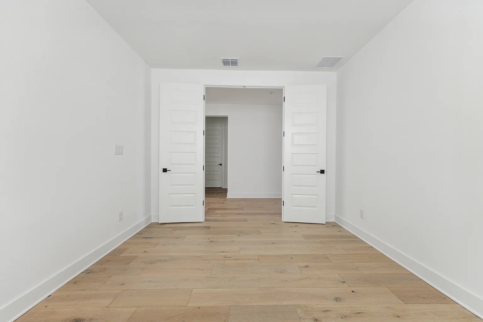 1909 Varese Path Leander, TX 78641 - Photo 23 of 40 Blonde hardwood floors flow through an airy space, connecting two rooms via double panel doors.
