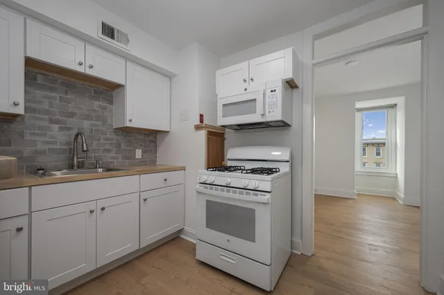 a kitchen with granite countertop white cabinets and white appliances
