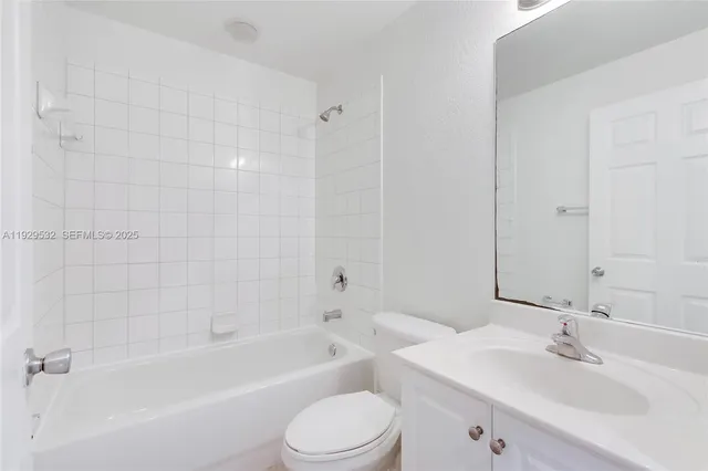 a bathroom with a bathtub shower sink vanity mirror and toilet