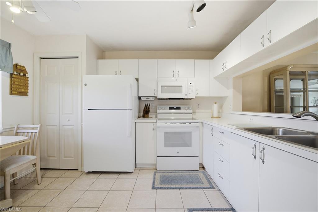 1001 Eastham Way, Unit C102 Naples, FL 34104 - Photo 13 of 41 a kitchen with white cabinets and white appliances