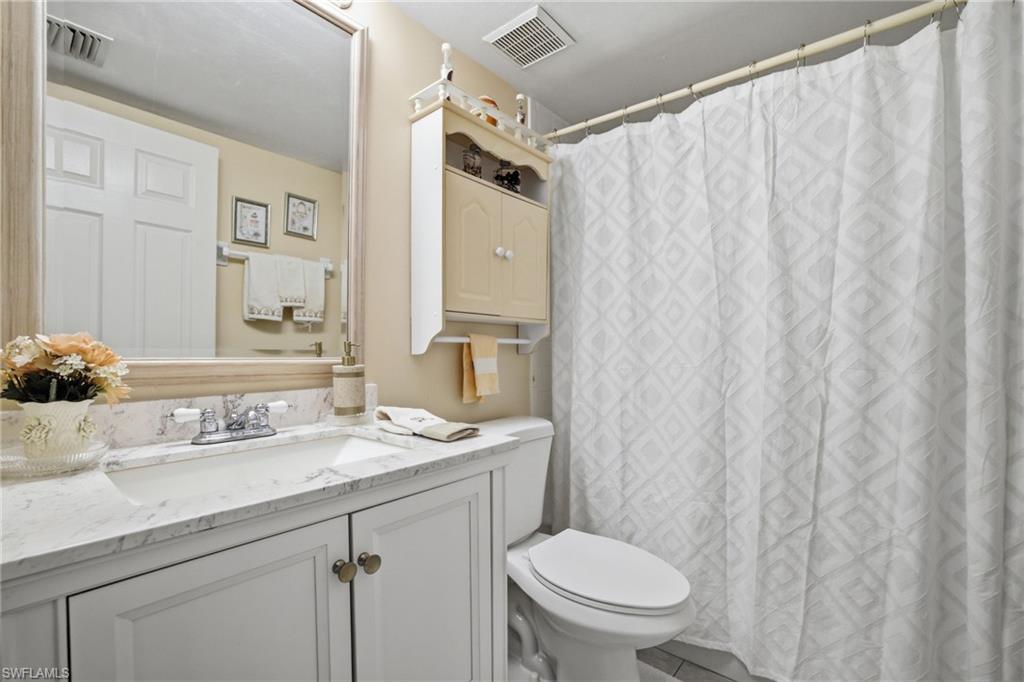 1001 Eastham Way, Unit C102 Naples, FL 34104 - Photo 17 of 41 a bathroom with a sink a toilet and shower curtain