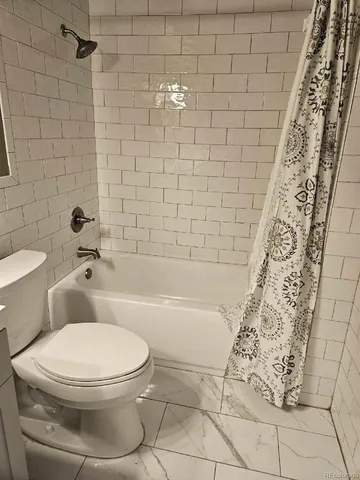 a white toilet sitting next to a bath tub and a shower