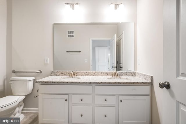 a bathroom with a granite countertop sink vanity mirror and toilet