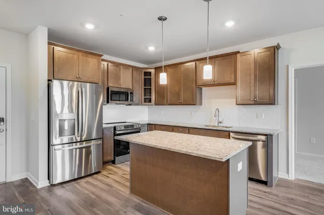 a kitchen with stainless steel appliances granite countertop a refrigerator a sink and a stove