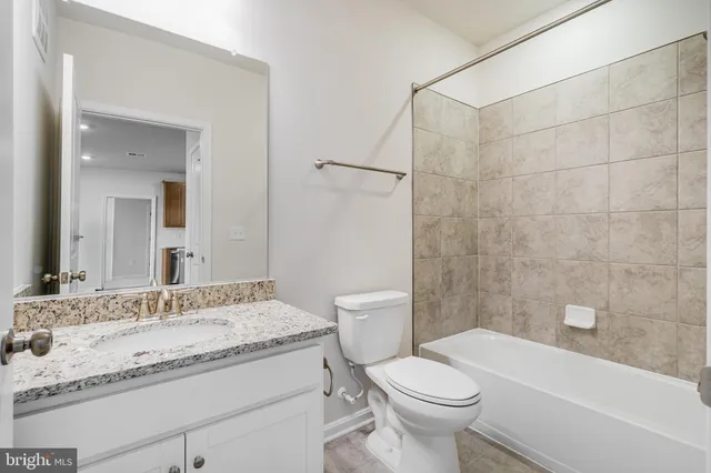 a bathroom with a granite countertop sink a toilet and shower