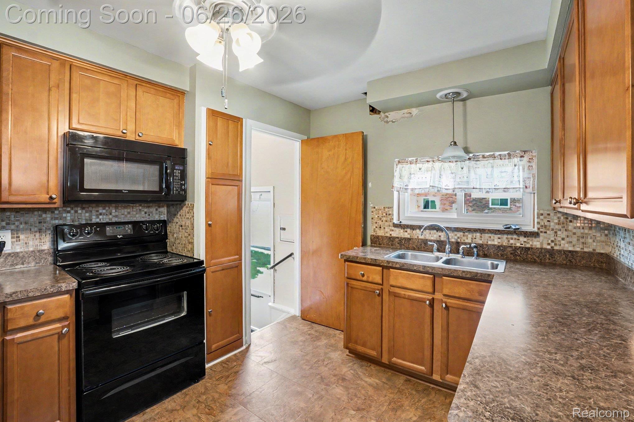 1209 Massoit Road Clawson, MI 48017 - Photo 12 of 25 Kitchen featuring wood cabinetry, black appliances, a double basin sink, and mosaic tile backsplash