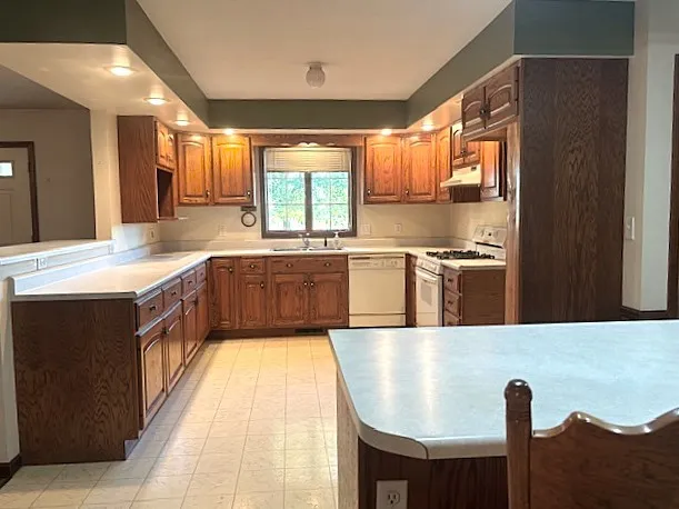 a large kitchen with stainless steel appliances granite countertop a sink and a refrigerator