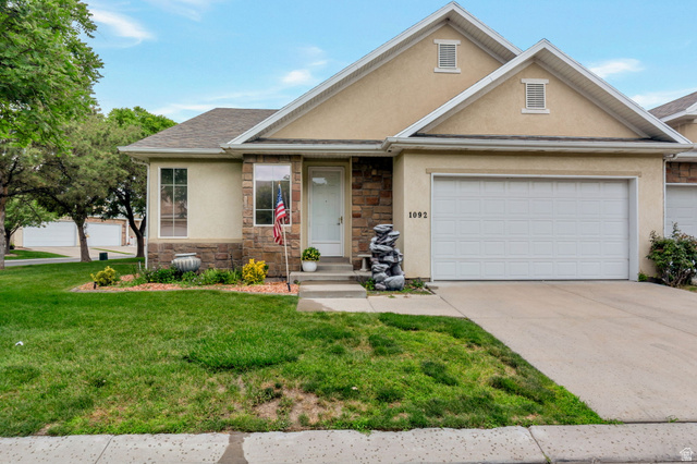 1092 Tithing Ridge Drive Riverton, UT 84065 - Photo 1 of 25 Stucco exterior with stone accenting, prominent attached garage, front entryway, and a sloped roofline