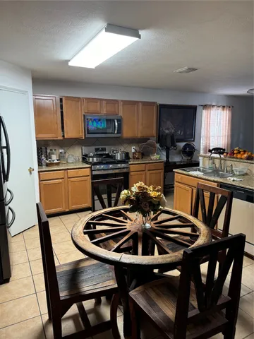 a kitchen with stainless steel appliances granite countertop a stove a sink dishwasher a dining table and chairs