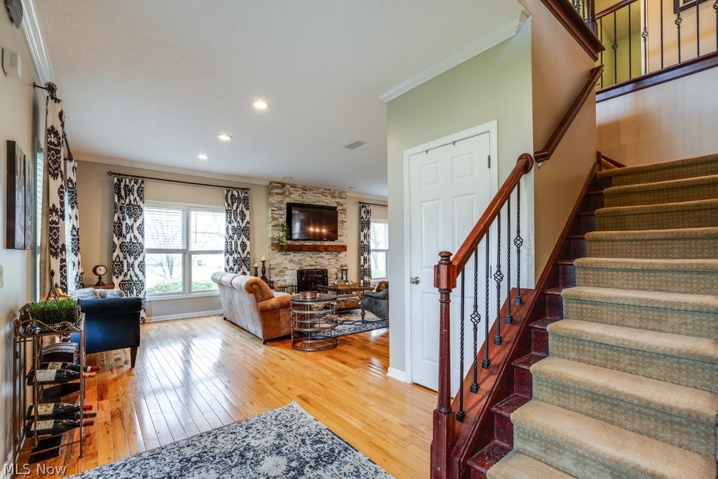 6325 Brecksville Road Independence, OH 44131 - Photo 5 of 50 The property features hardwood flooring in the main living area, a stone-faced fireplace, and a staircase with a dark wood banister and wrought iron spindles
