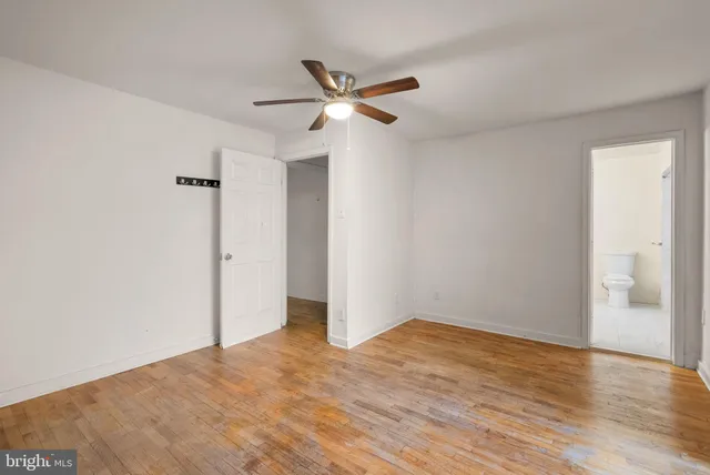 a view of empty room with wooden floor and ceiling fan