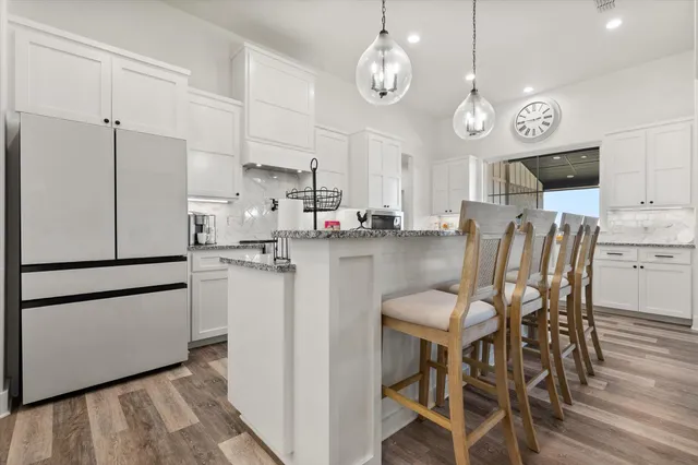 a kitchen with stainless steel appliances a refrigerator a stove a dining table and chairs with wooden floor