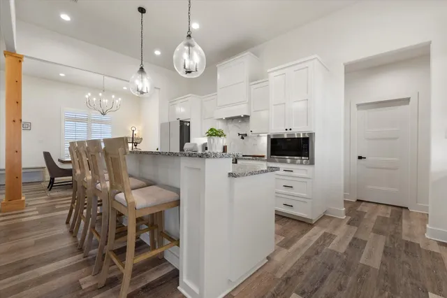 a kitchen with stainless steel appliances kitchen island granite countertop a table chairs and a refrigerator