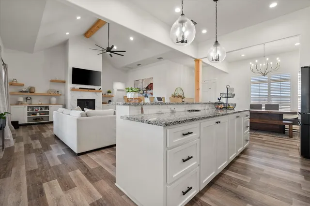 a large white kitchen with a large island in the center and a wooden floors