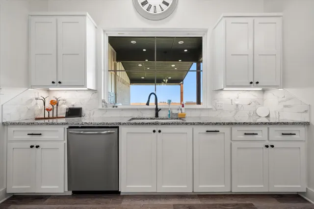 a kitchen with granite countertop white cabinets and sink