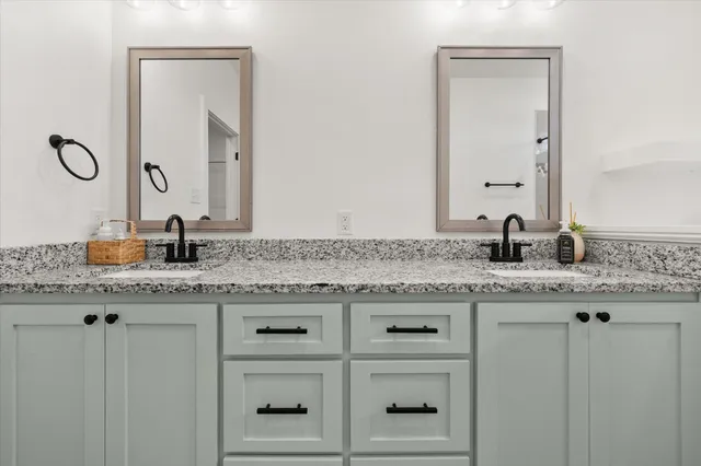 a bathroom with a granite countertop double vanity sink and mirror