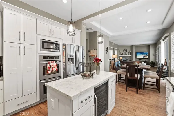 a kitchen with stainless steel appliances kitchen island granite countertop a table chairs and a refrigerator