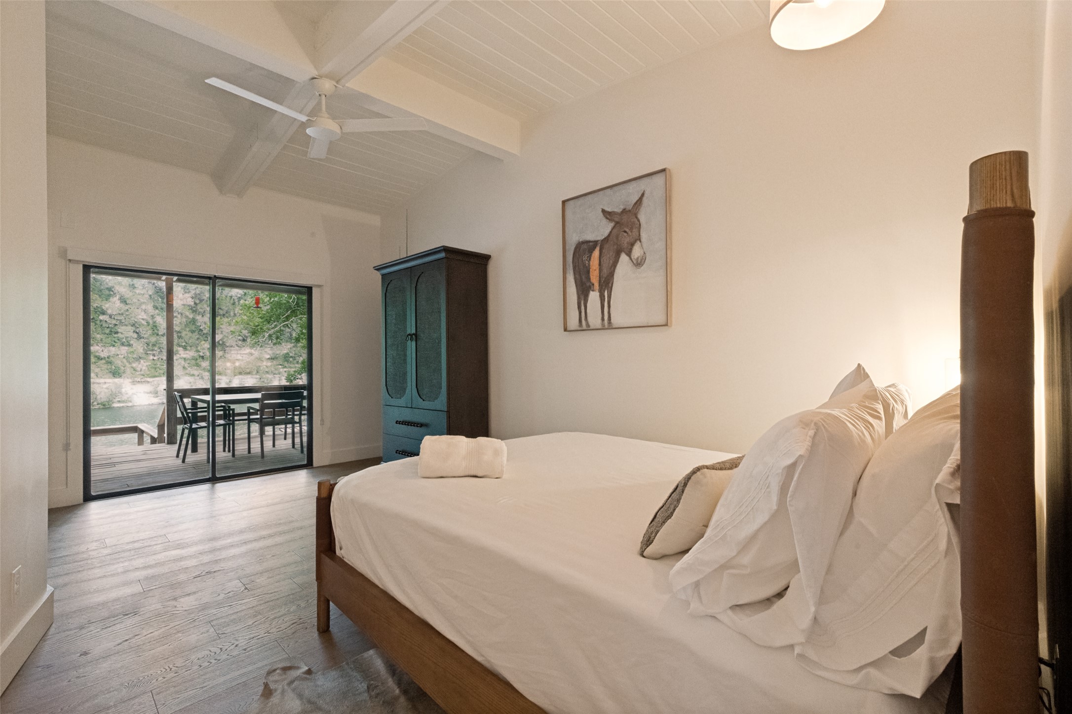 303 Lago Verde Road Austin, TX 78734 - Photo 25 of 39 Step into a comfortable bedroom featuring vaulted ceilings, sleek wood flooring, and a sliding glass door leading to a scenic outdoor patio.