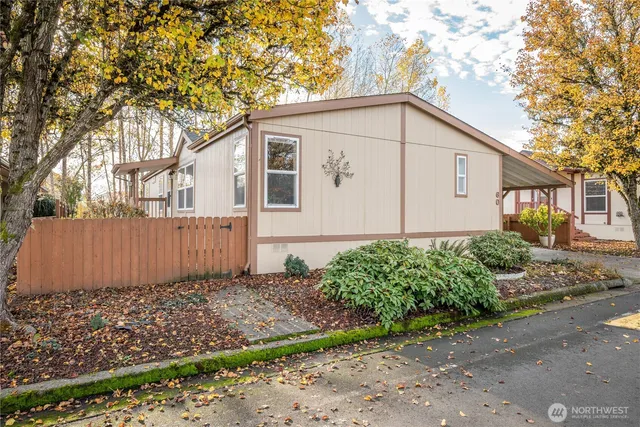 a view of a small house with a small yard plants and large tree