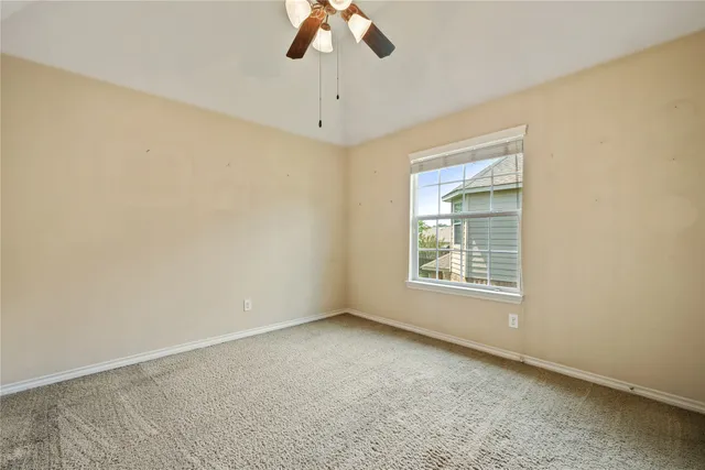 an empty room with a chandelier fan and windows