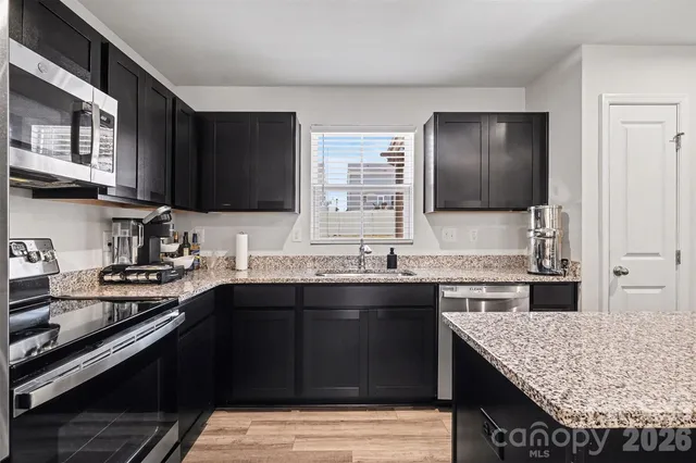 a kitchen with stainless steel appliances granite countertop a sink stove and cabinets