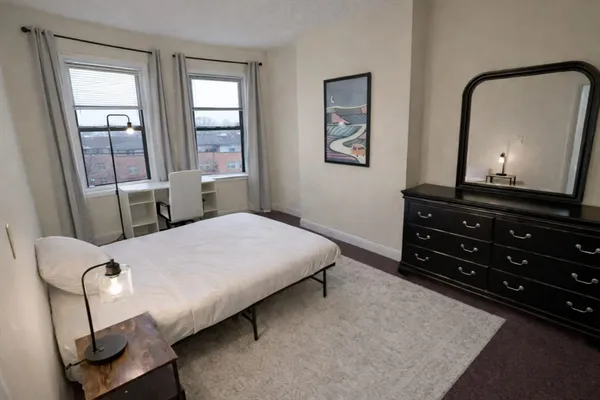 a bedroom with a bed and a mirror on dresser