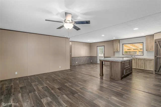 a view of kitchen and empty room with wooden floor