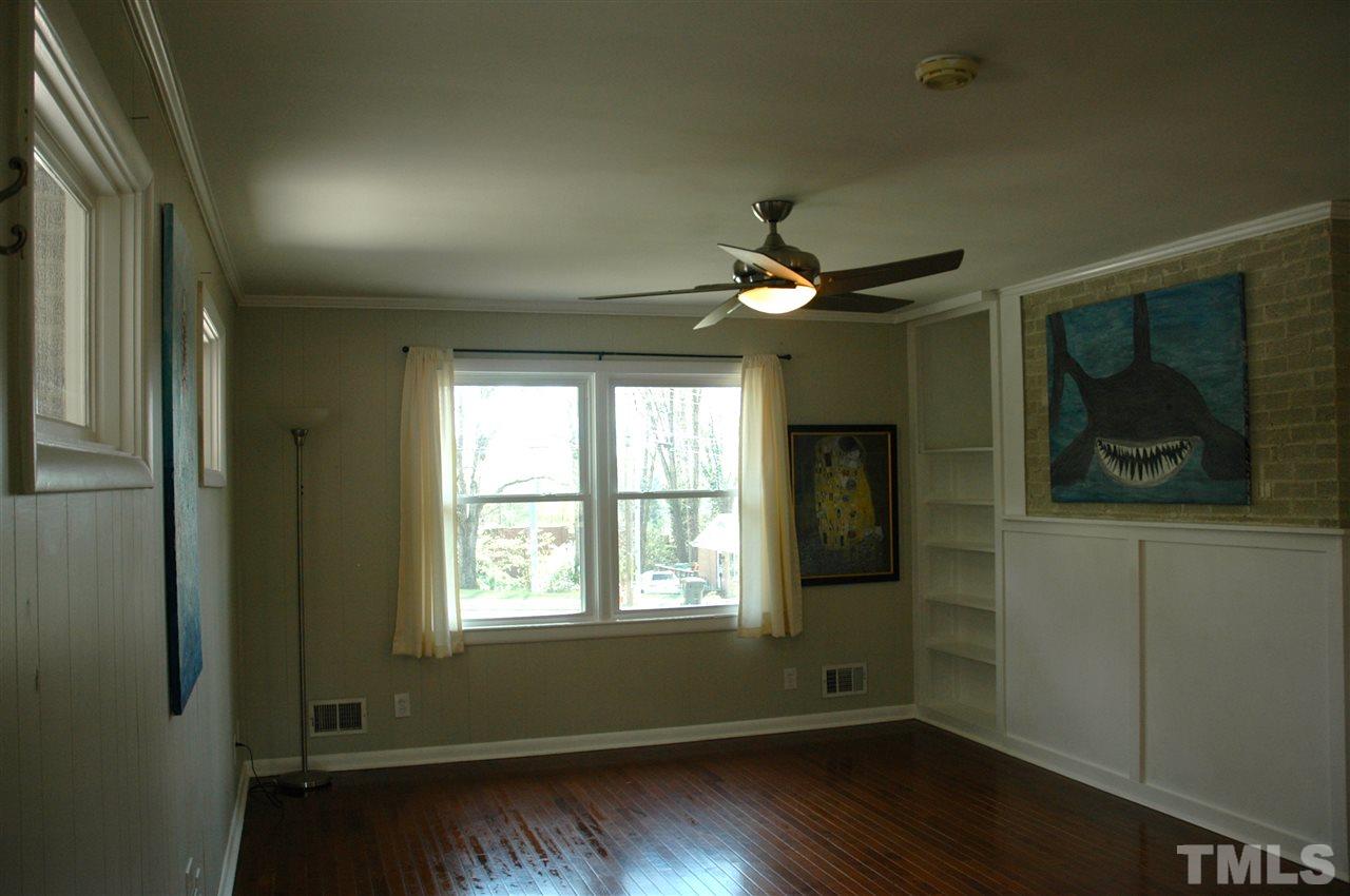 716 Currituck Drive Raleigh, NC 27609 - Photo 7 of 19 Features hardwood floors, paneling, built in bookshelf, & exposed brick accent wall.