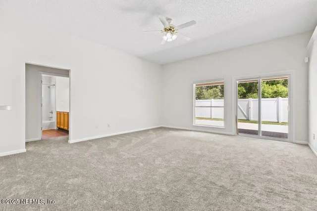 an empty room with windows and ceiling fan