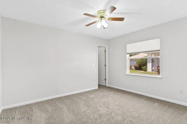 an empty room with a window and a fan