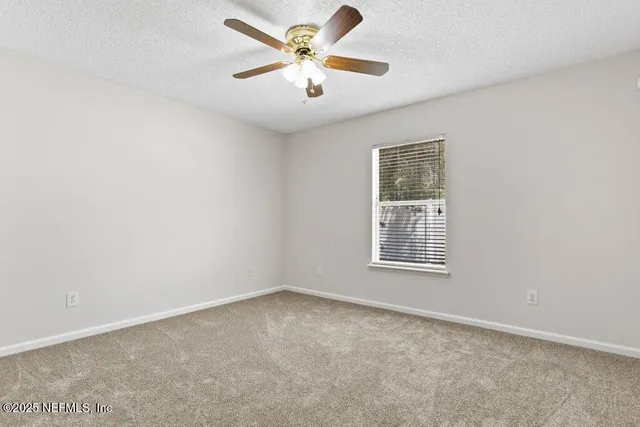 an empty room with a window and a fan
