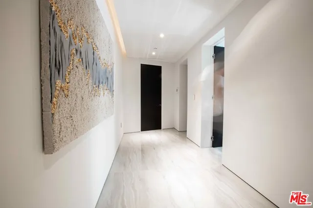 a view of a hallway with wooden floor and a bathroom