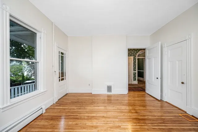 a view of empty room with wooden floor and fan