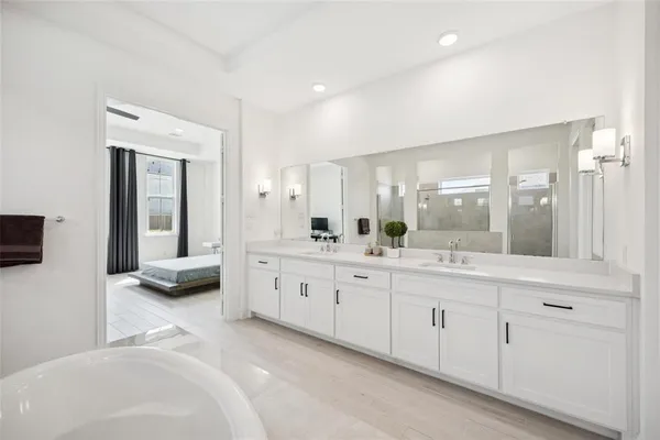 a spacious bathroom with a granite countertop double vanity mirror and a bathtub
