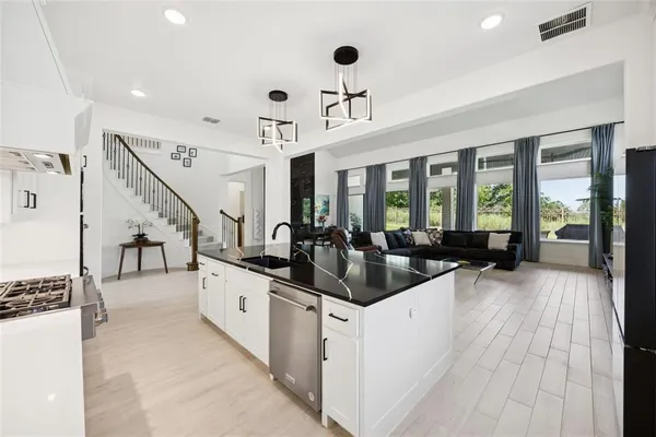 a large white kitchen with a large window and stainless steel appliances