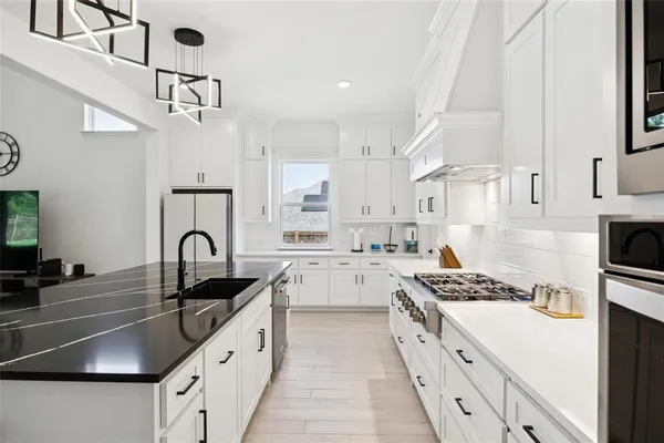 a kitchen with stainless steel appliances a sink a stove and cabinets