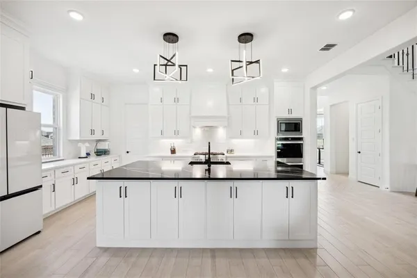 a kitchen with granite countertop a sink and white cabinets