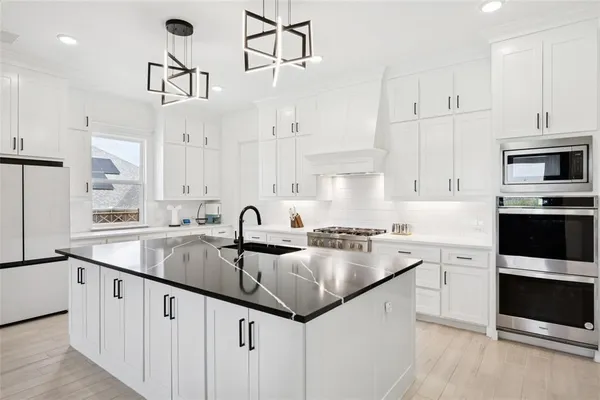 a kitchen with granite countertop a sink stainless steel appliances and white cabinets