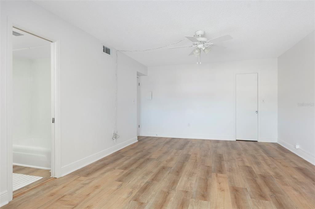 4725 Cove Circle, Unit 207 St. Petersburg, FL 33708 - Photo 12 of 46 a view of a room with wooden floor and a ceiling fan