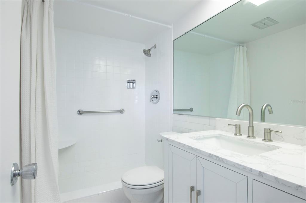 4725 Cove Circle, Unit 207 St. Petersburg, FL 33708 - Photo 13 of 46 a bathroom with a granite countertop sink toilet and shower