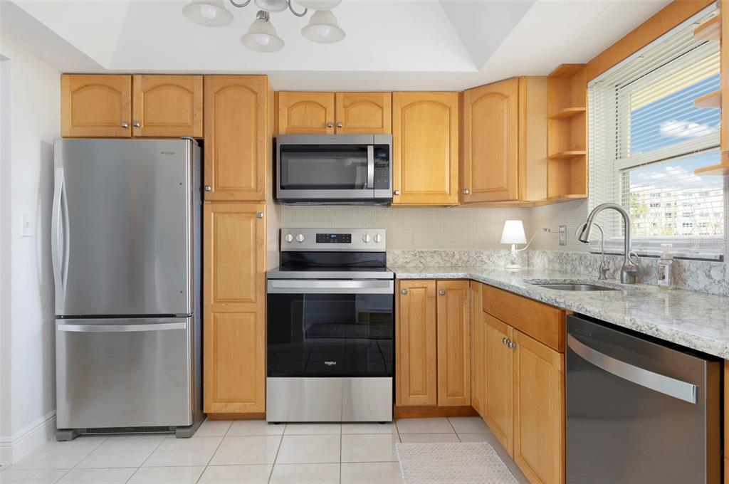4725 Cove Circle, Unit 207 St. Petersburg, FL 33708 - Photo 8 of 46 a kitchen with stainless steel appliances granite countertop a refrigerator sink and microwave