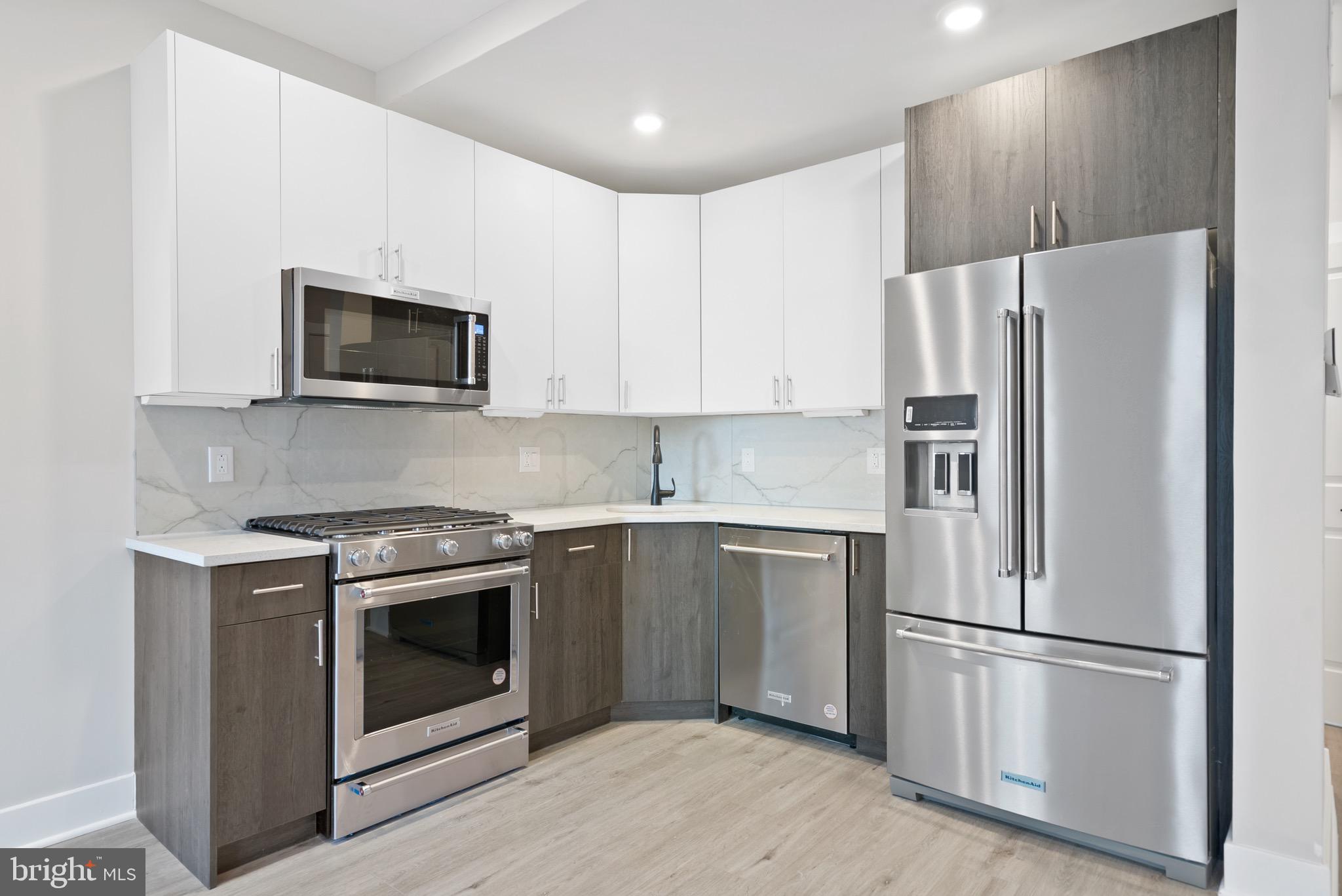 a kitchen with stainless steel appliances granite countertop a refrigerator stove a sink and a microwave