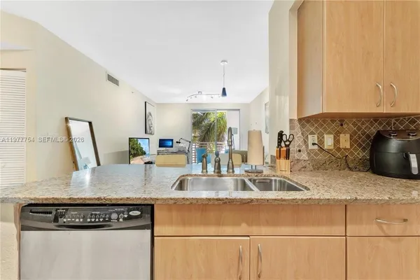 a kitchen with granite countertop a sink a stove and a wooden cabinets