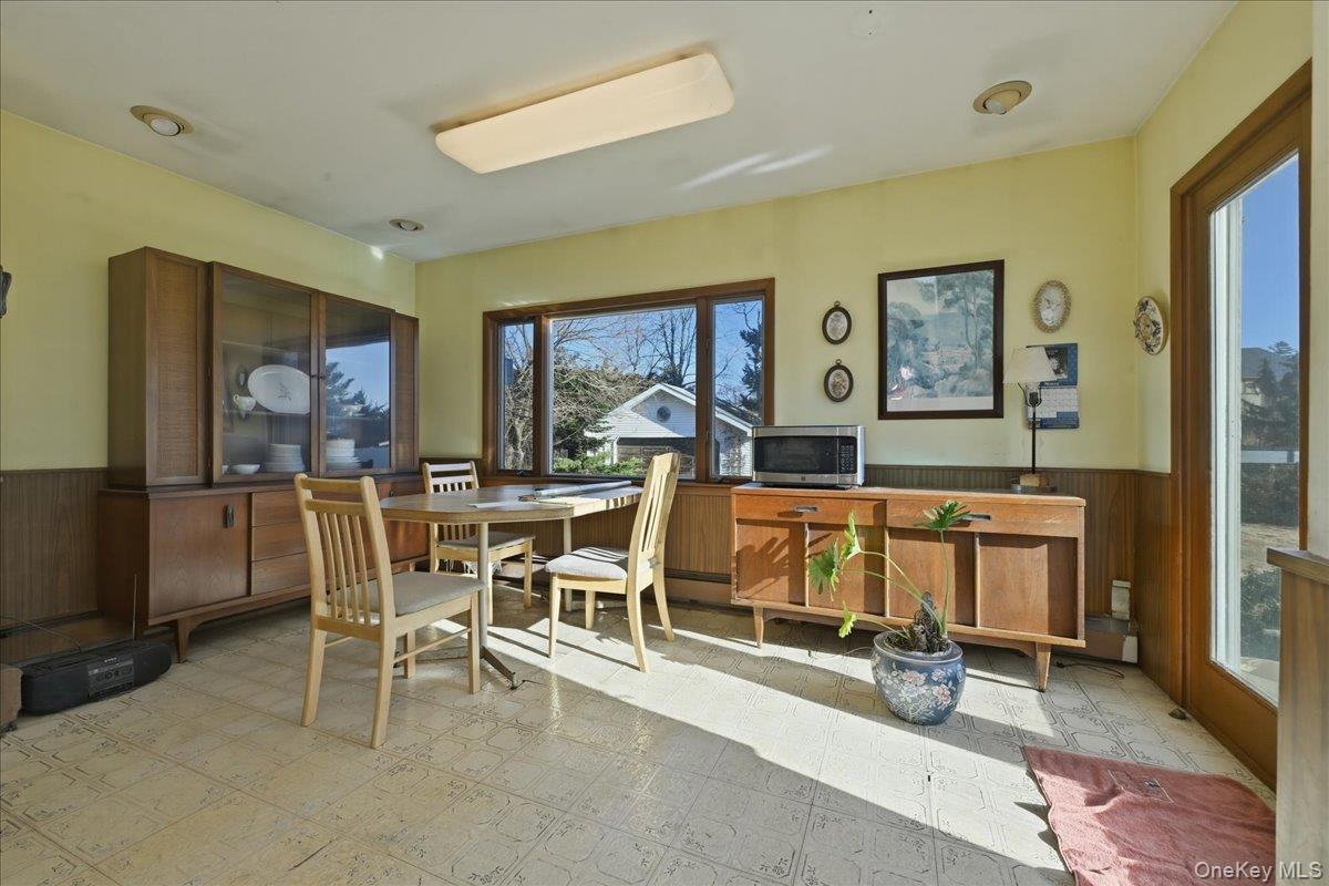 590 Waterview Road Oceanside, NY 11572 - Photo 9 of 26 a living room with a couch a dining table and paintings on the wall